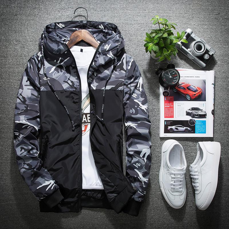 Camouflage lightweight hoodie for men on display with shoes, magazine, and camera.