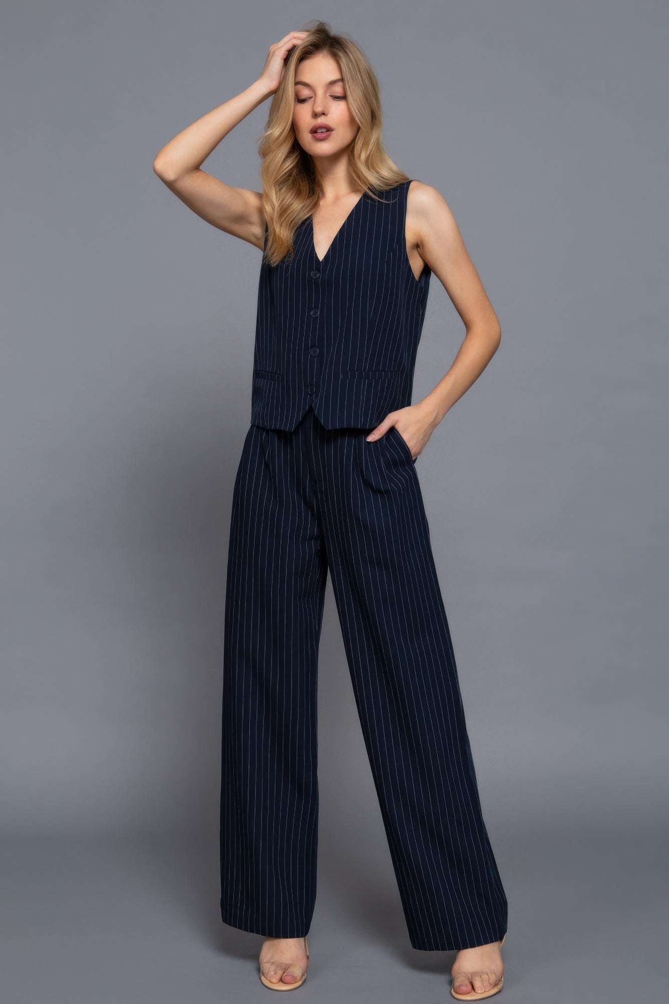 Navy and white pinstripe woven straight pants with a matching vest on a model against a gray background.