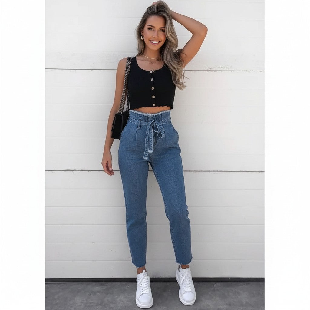 Model wearing GIGI & POPO high-waisted belted denim jeans with raw hem, paired with a black crop top and sneakers.